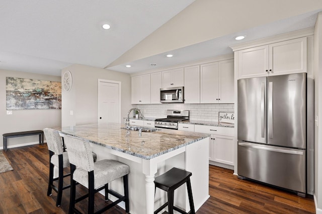 kitchen featuring appliances with stainless steel finishes, white cabinetry, dark hardwood / wood-style floors, a kitchen island with sink, and sink