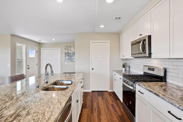 kitchen with light stone counters, sink, dark wood-type flooring, white cabinetry, and stainless steel appliances