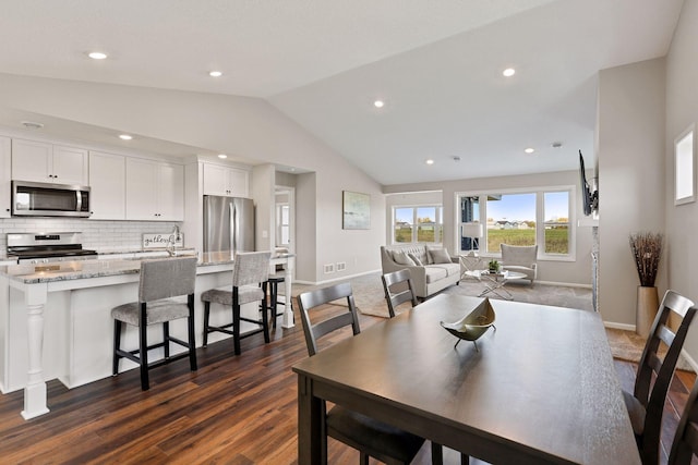 dining area with vaulted ceiling and dark wood-type flooring