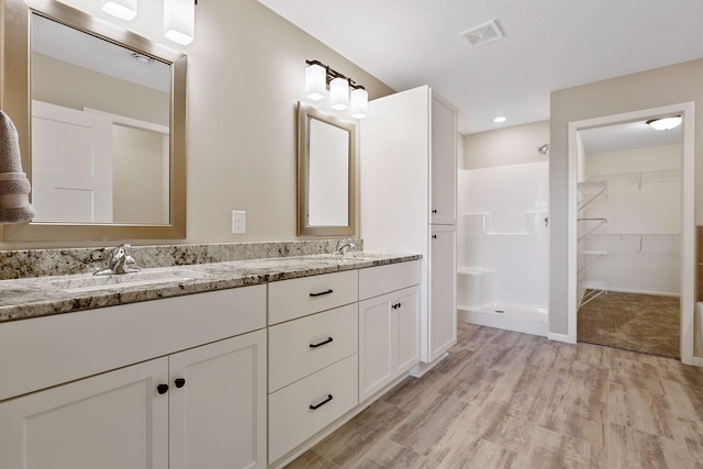 bathroom featuring walk in shower, a textured ceiling, vanity, and hardwood / wood-style floors