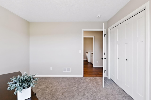 unfurnished bedroom featuring a textured ceiling, a closet, and carpet