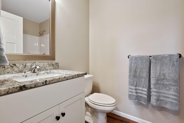 bathroom with a shower, hardwood / wood-style flooring, vanity, and toilet