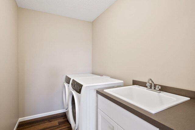 laundry room featuring a textured ceiling, sink, washer and clothes dryer, and dark hardwood / wood-style flooring