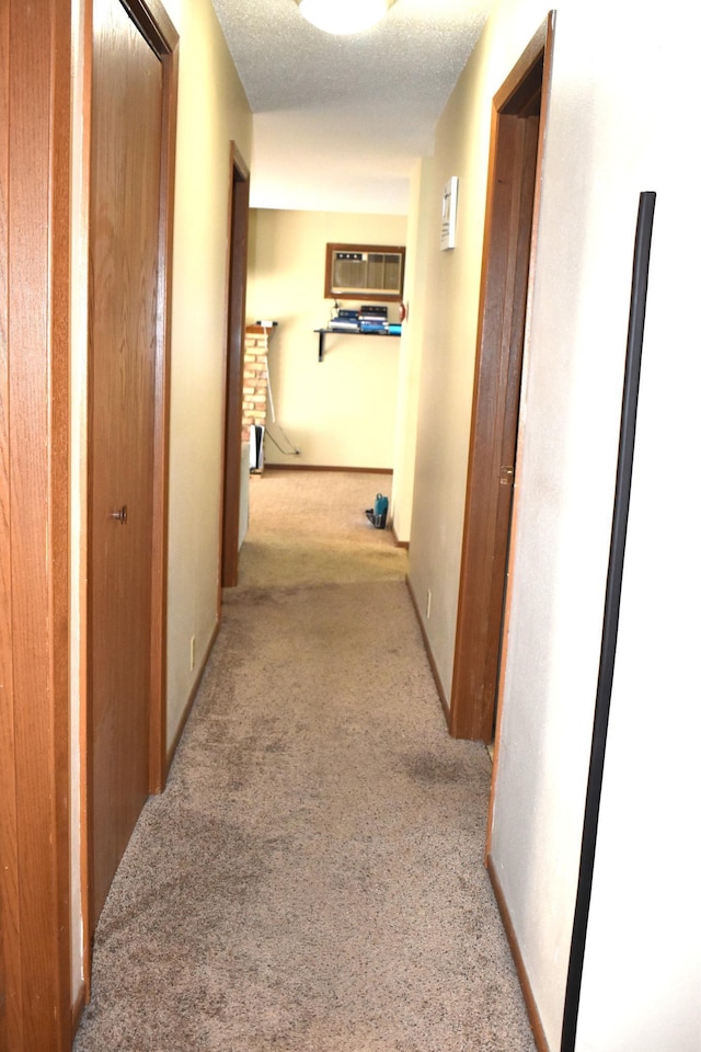 hallway featuring light carpet, an AC wall unit, and a textured ceiling