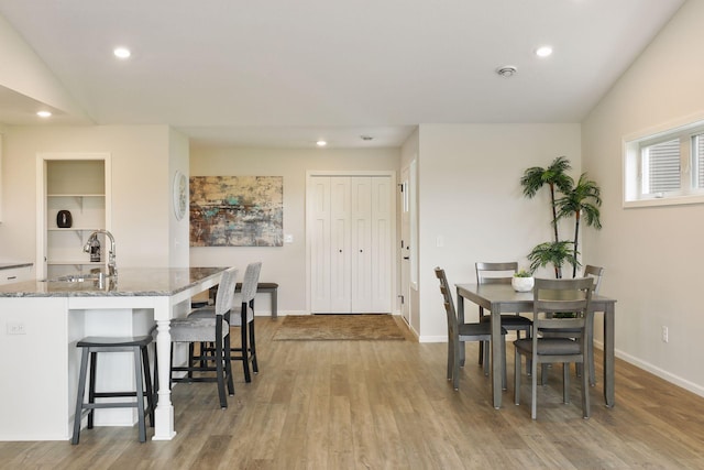 dining space featuring lofted ceiling, light hardwood / wood-style floors, and sink