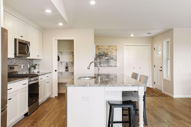 kitchen featuring stainless steel appliances, hardwood / wood-style flooring, a kitchen island with sink, and sink