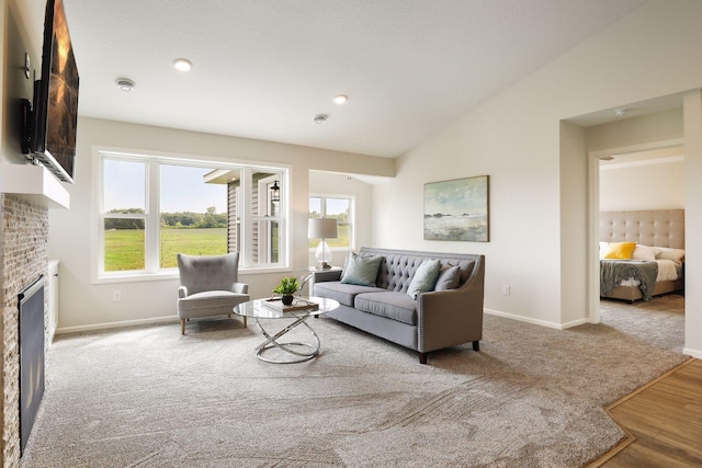 living room featuring a brick fireplace, lofted ceiling, and light hardwood / wood-style flooring