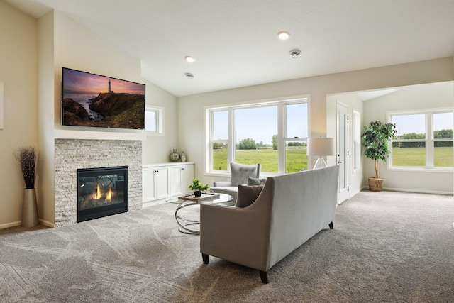 living room featuring carpet, vaulted ceiling, a healthy amount of sunlight, and a stone fireplace