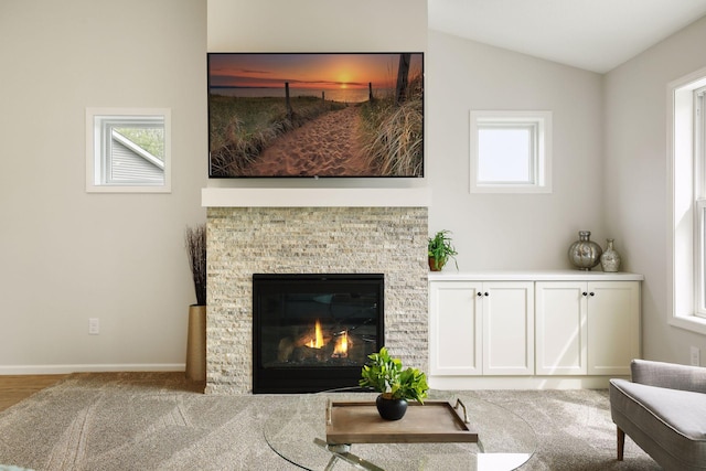 living room featuring a fireplace, vaulted ceiling, and light hardwood / wood-style flooring