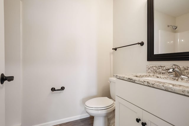 bathroom with walk in shower, hardwood / wood-style floors, vanity, and toilet