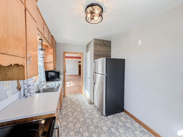 kitchen featuring stove, light wood-type flooring, stainless steel fridge, and sink