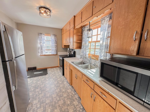 kitchen featuring appliances with stainless steel finishes, sink, and decorative light fixtures