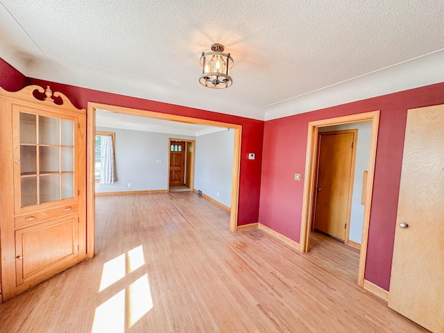 interior space with a notable chandelier, light hardwood / wood-style floors, and a textured ceiling