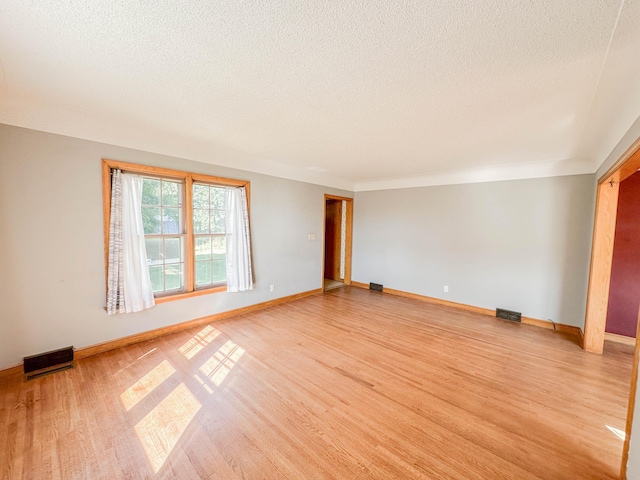 unfurnished room featuring a textured ceiling and light hardwood / wood-style floors