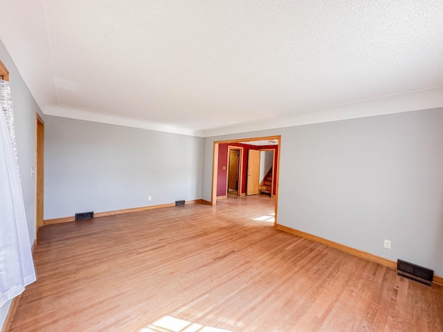 unfurnished room featuring light wood-type flooring and a textured ceiling