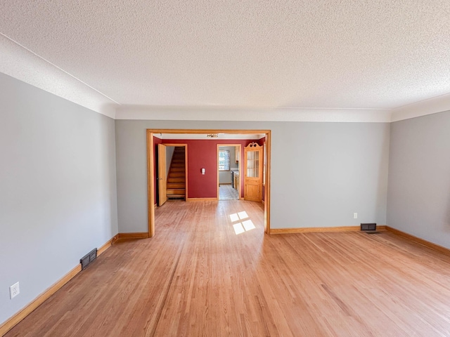 unfurnished room with light wood-type flooring and a textured ceiling