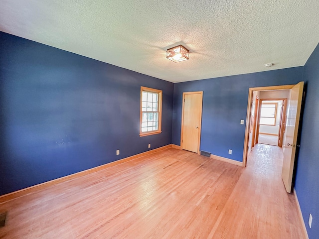 unfurnished bedroom with a textured ceiling and wood-type flooring