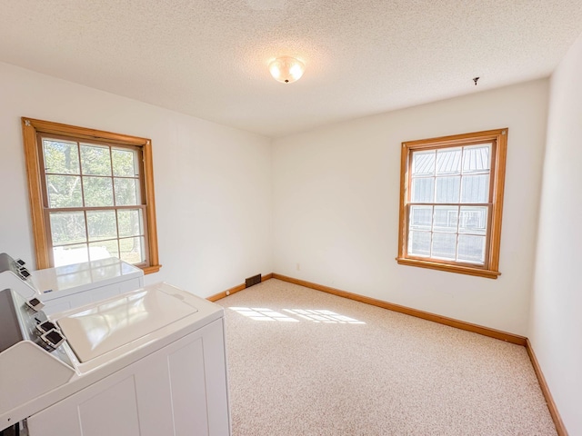 interior space with a textured ceiling, plenty of natural light, and washing machine and clothes dryer