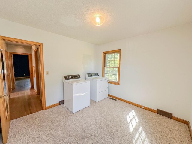 washroom with carpet, a textured ceiling, and independent washer and dryer