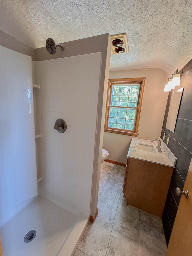 bathroom featuring walk in shower, a textured ceiling, vanity, and toilet