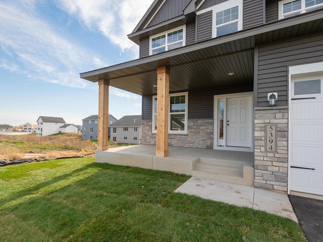 property entrance with a porch, a garage, and a lawn