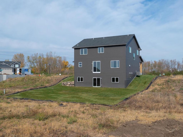 rear view of house featuring cooling unit and a lawn