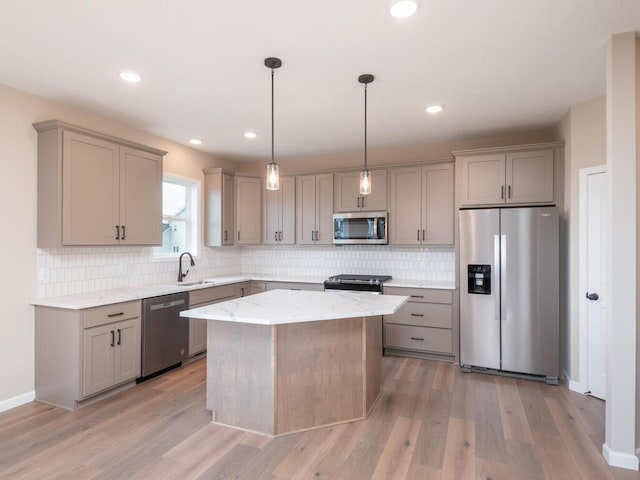 kitchen with light hardwood / wood-style flooring, sink, a center island, decorative light fixtures, and appliances with stainless steel finishes