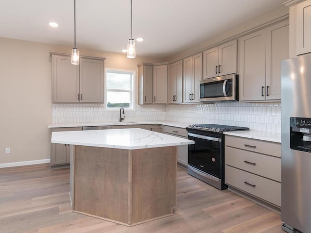 kitchen with light hardwood / wood-style floors, stainless steel appliances, pendant lighting, and a kitchen island