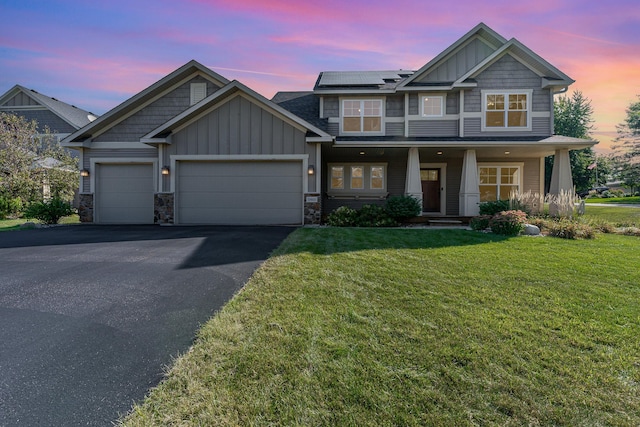 craftsman-style home with solar panels, covered porch, a lawn, and a garage