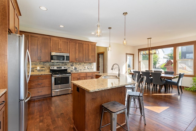 kitchen with a center island with sink, appliances with stainless steel finishes, dark wood-type flooring, and sink