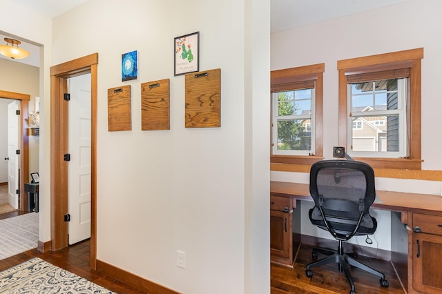 home office featuring dark hardwood / wood-style flooring and built in desk