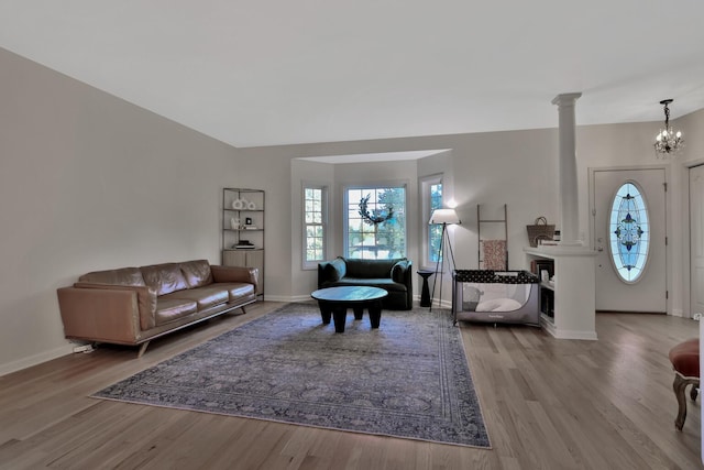 living room featuring decorative columns, light hardwood / wood-style floors, and an inviting chandelier