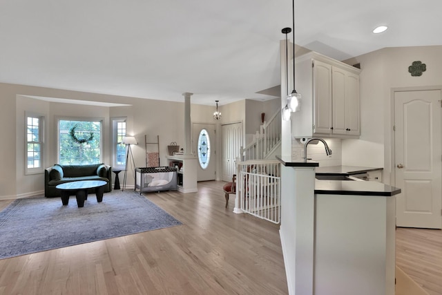 kitchen featuring white cabinets, light wood-type flooring, pendant lighting, and decorative backsplash