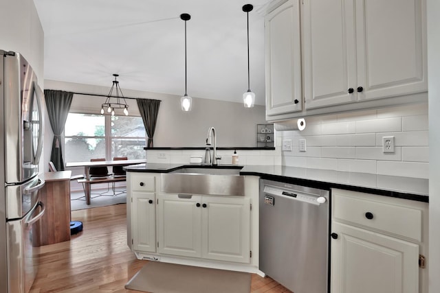 kitchen featuring hanging light fixtures, sink, white cabinetry, appliances with stainless steel finishes, and light hardwood / wood-style floors