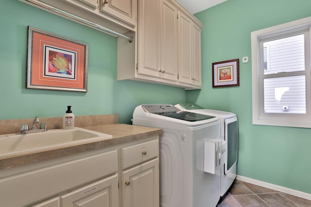 washroom with sink, washer and dryer, dark tile patterned floors, and cabinets