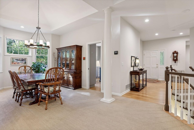 carpeted dining area with a chandelier and decorative columns