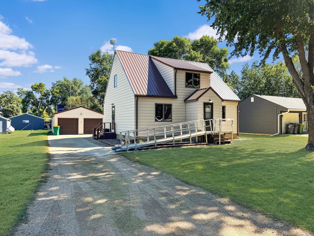 view of front of home featuring a garage, a front yard, and an outbuilding