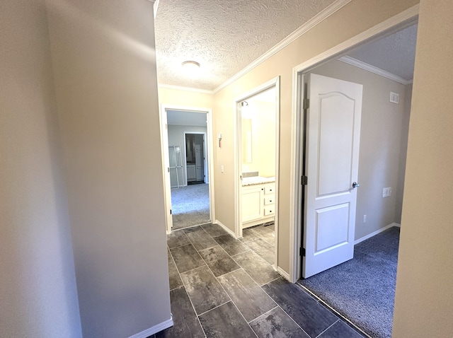 hall featuring a textured ceiling, crown molding, and dark colored carpet