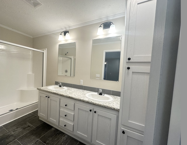 bathroom with vanity, a textured ceiling, ornamental molding, hardwood / wood-style floors, and an enclosed shower