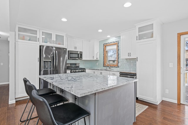 kitchen with a center island, dark wood finished floors, stainless steel appliances, backsplash, and a sink