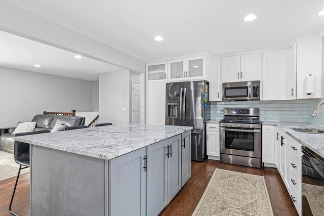 kitchen featuring dark wood-style floors, stainless steel appliances, light stone counters, and a sink