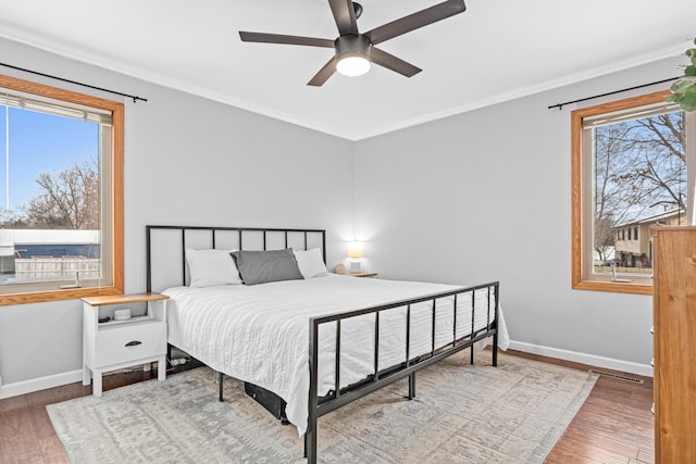 bedroom featuring baseboards, wood finished floors, and ornamental molding