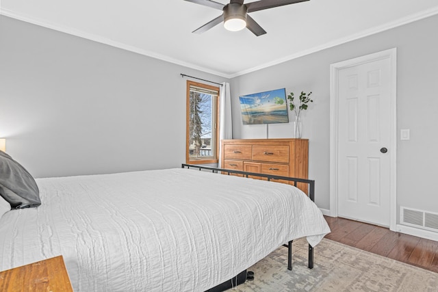 bedroom featuring ornamental molding, wood finished floors, and visible vents