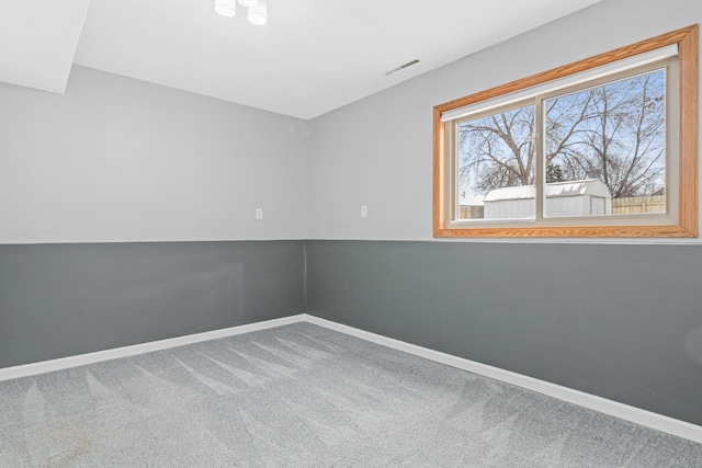 spare room with carpet floors, visible vents, and baseboards