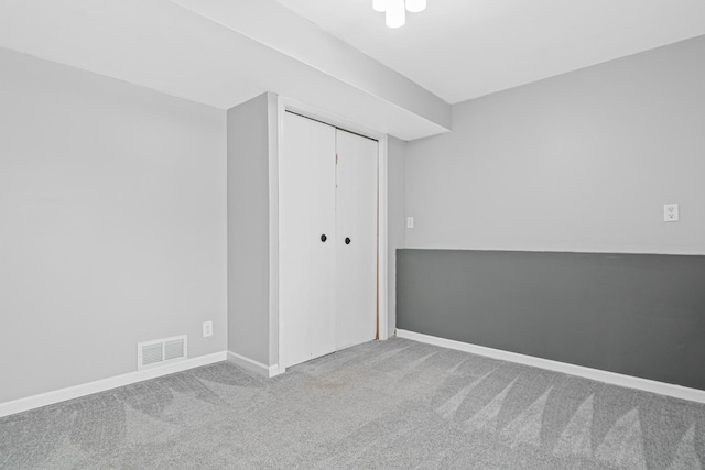 carpeted empty room featuring baseboards and visible vents