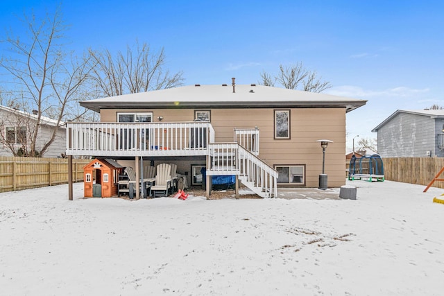 snow covered house with a fenced backyard, stairs, and a wooden deck