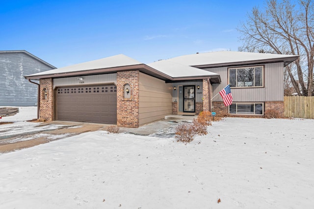 view of front facade featuring brick siding, fence, and an attached garage