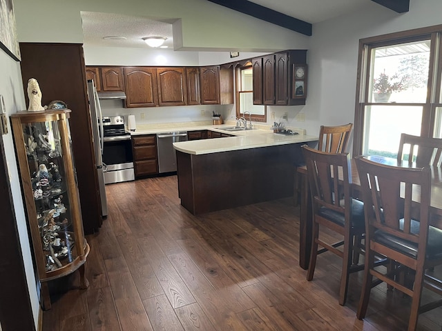 kitchen with sink, kitchen peninsula, a textured ceiling, appliances with stainless steel finishes, and dark hardwood / wood-style floors