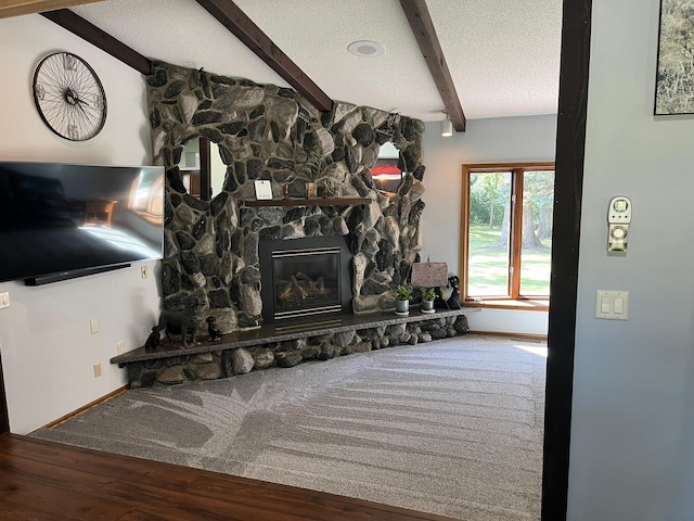 interior space featuring vaulted ceiling with beams, hardwood / wood-style flooring, a fireplace, and a textured ceiling