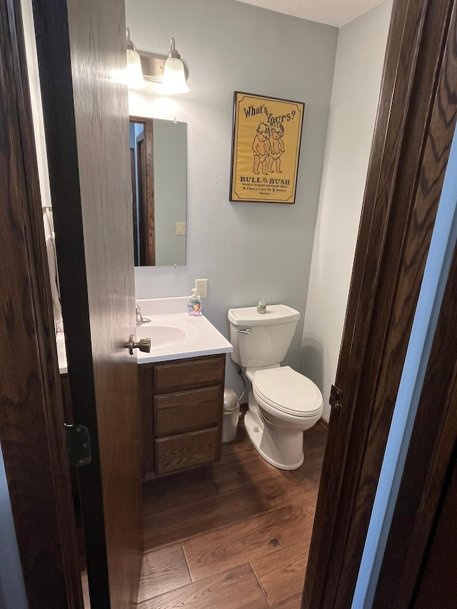 bathroom with hardwood / wood-style floors, toilet, vanity, and a textured ceiling